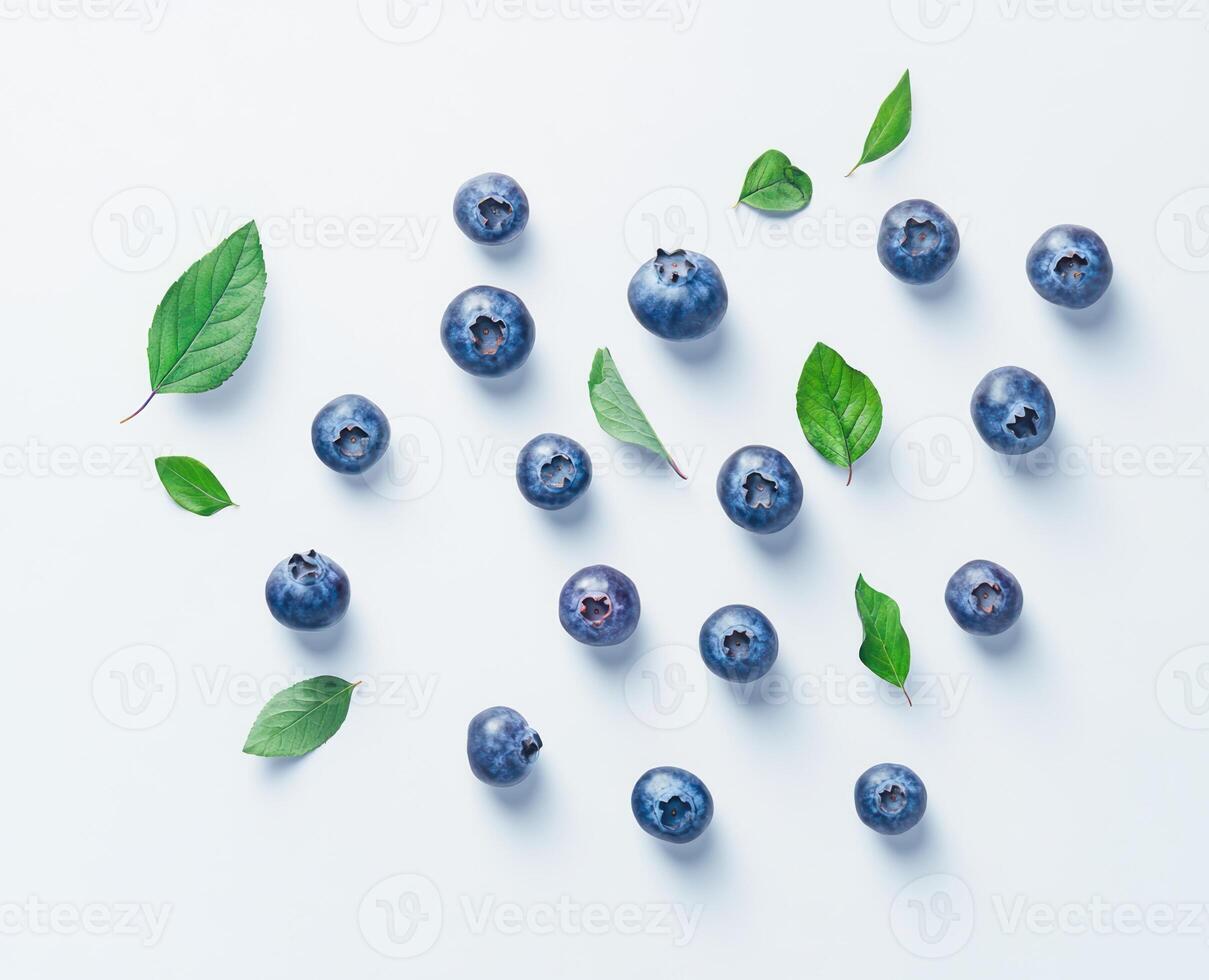 Blueberries and leaves scattered on a light-blue surface photo
