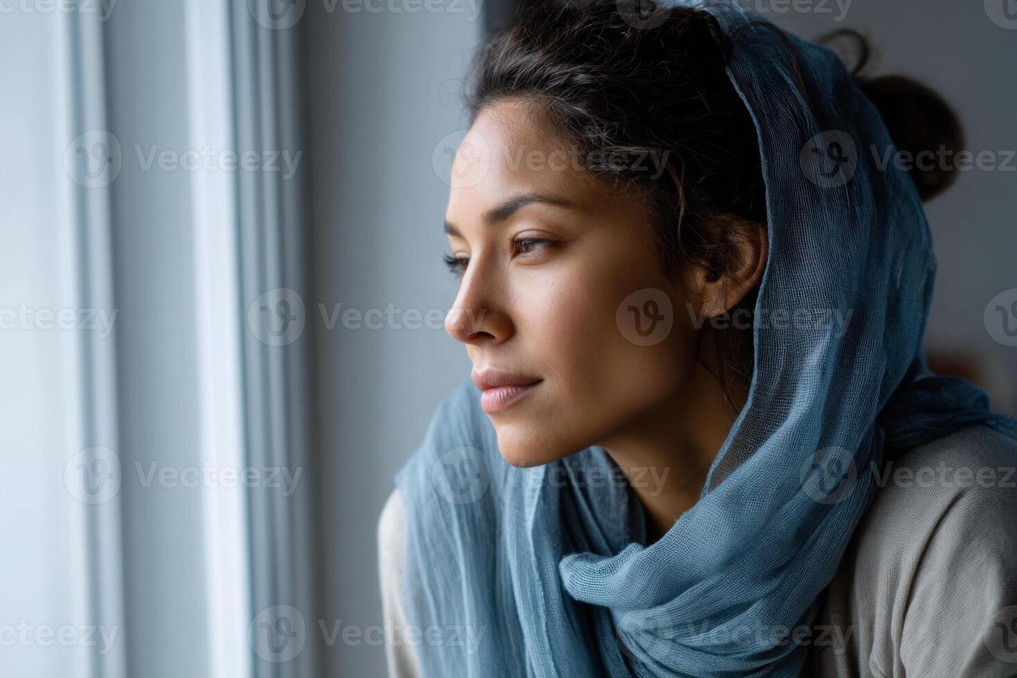 Thoughtful reflection and vulnerability of a young Middle-Eastern woman gazing out a window photo