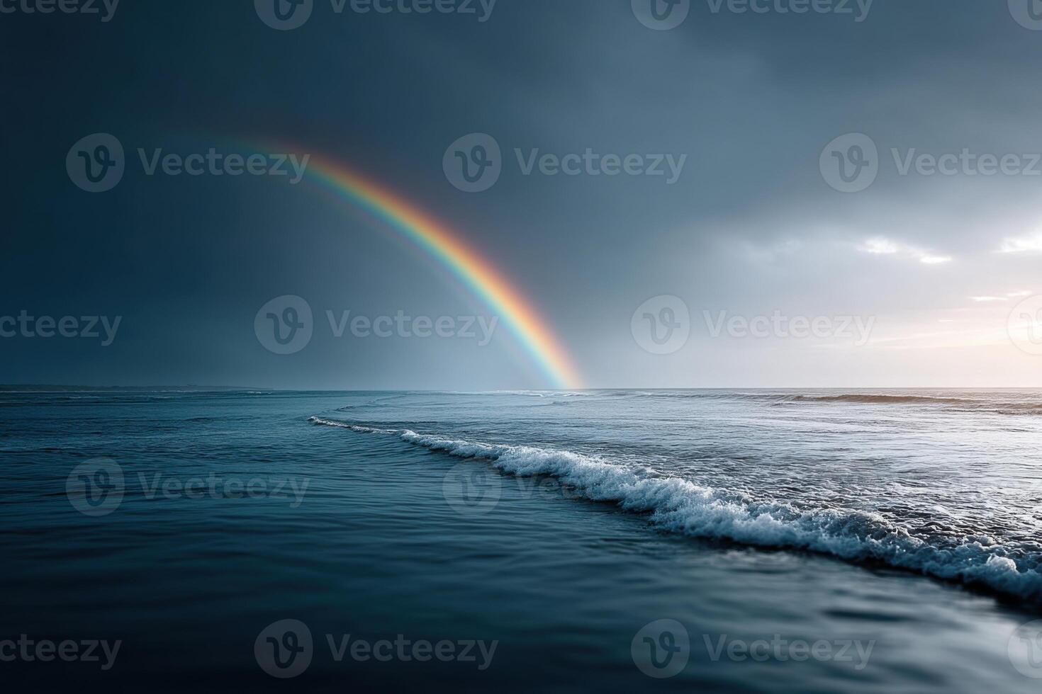 Dramatic sky with vivid rainbow arching above ocean waves at dusk photo