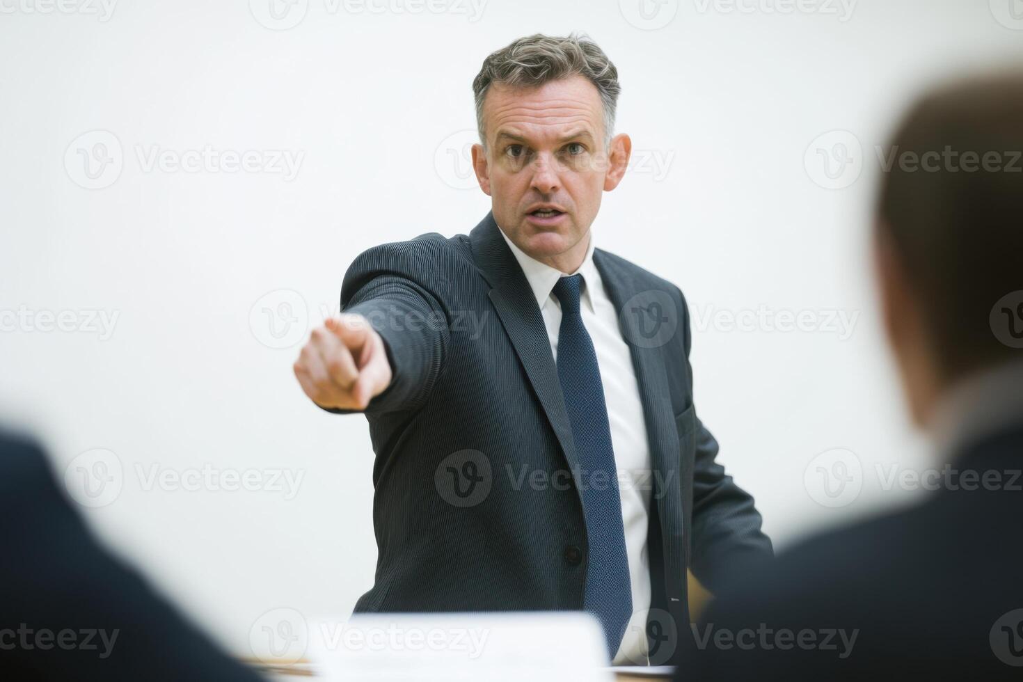 Middle-aged man addresses colleagues during a meeting while pointing out presentation errors photo
