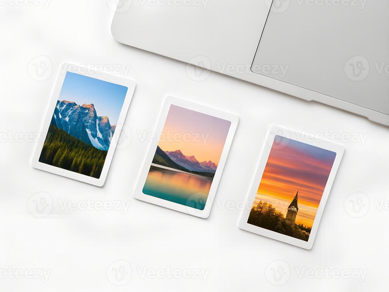 Three Landscape Photographs on a White Surface Near a Laptop photo