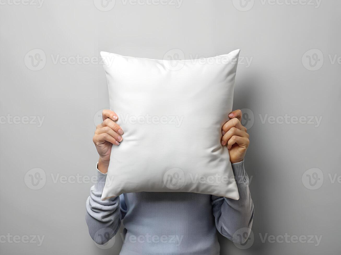 Person Hiding Face Behind White Pillow Against Gray Background photo
