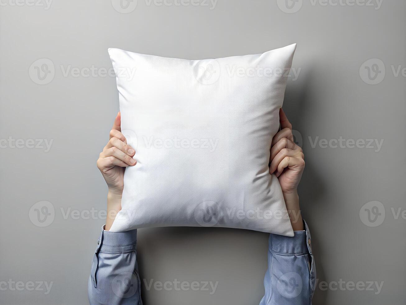 Overhead View of Hands Holding a Soft White Pillow Against a Gray Background photo