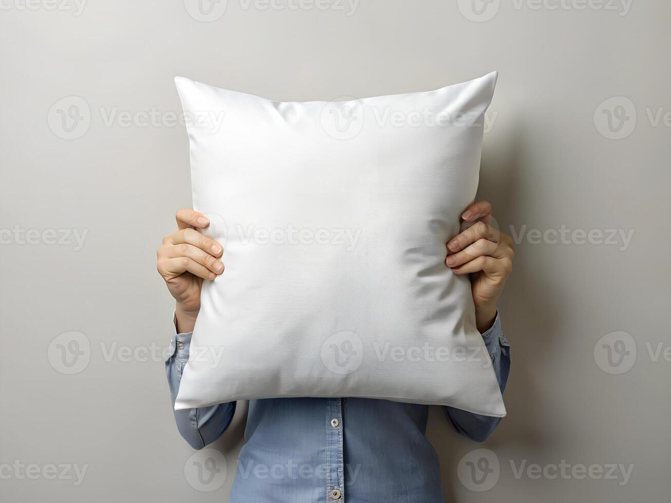 Person Hiding Face Behind Large White Pillow Against Gray Background photo