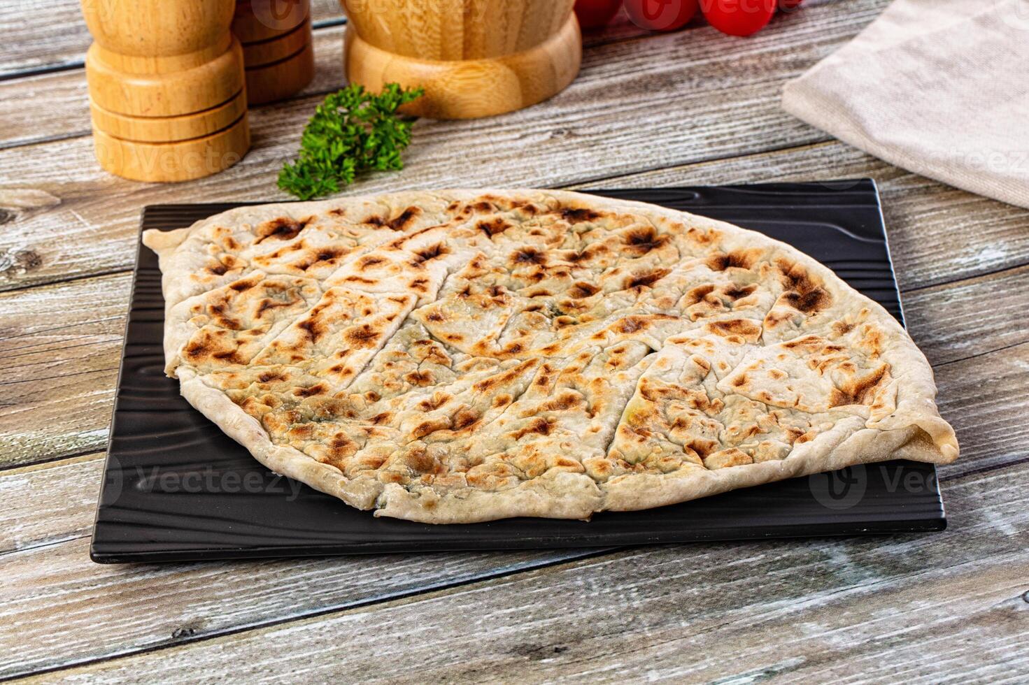 A flatbread on a black plate with some spices photo