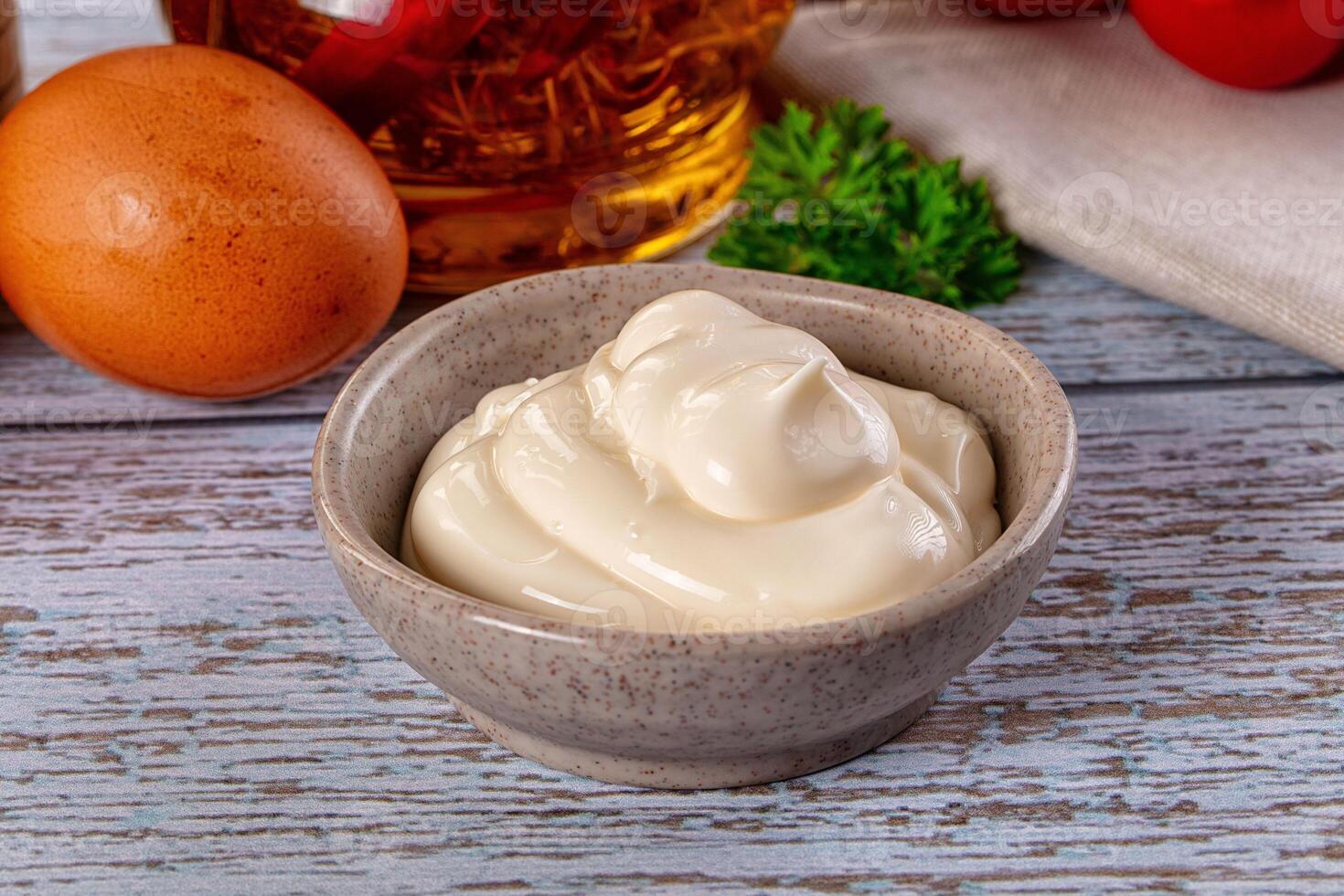 A bowl of sour cream next to eggs and tomatoes photo