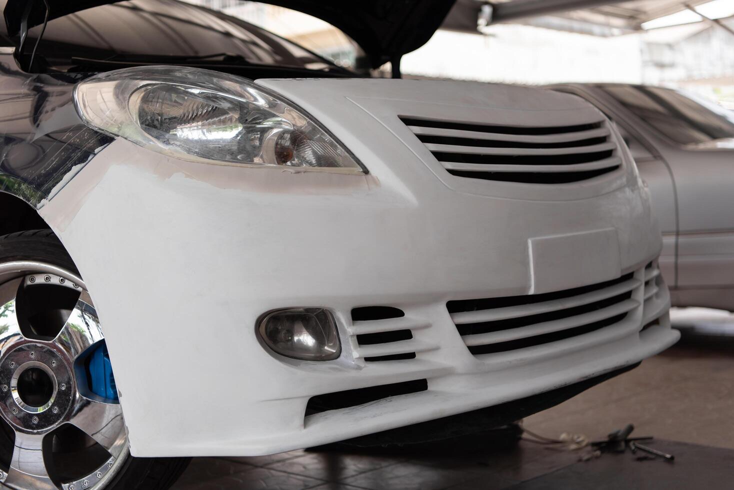 A white car is being worked on by a mechanic photo