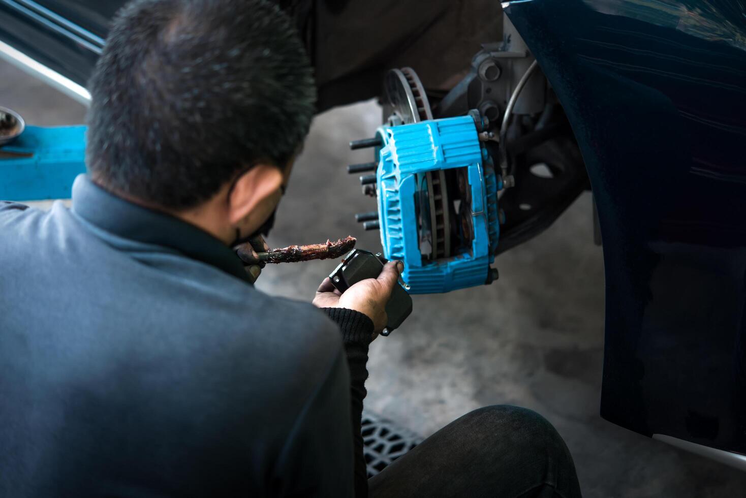 A man is working on a car with a blue brake photo