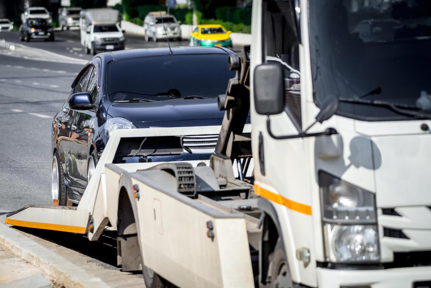 A tow truck is towing a car on the side of the road photo