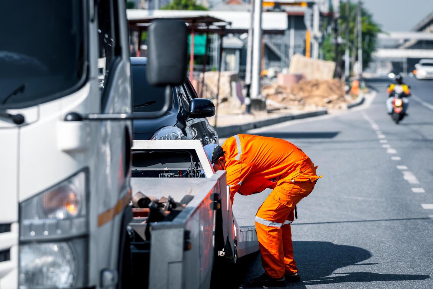 A man in an orange uniform is fixing a truck photo