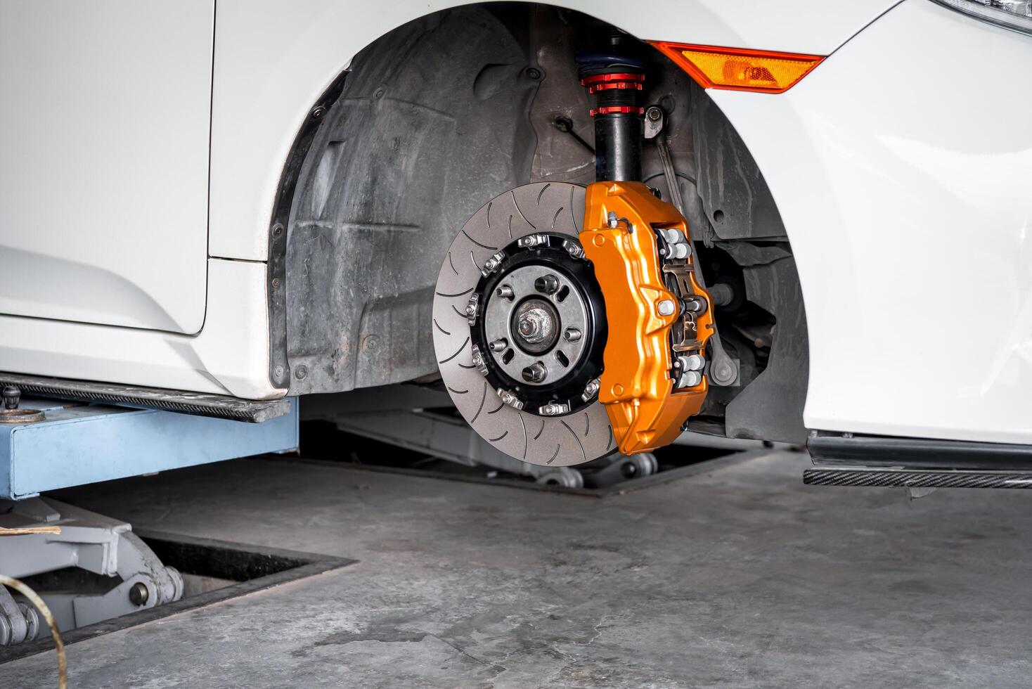 A white car with orange brake pads and a brake disc photo