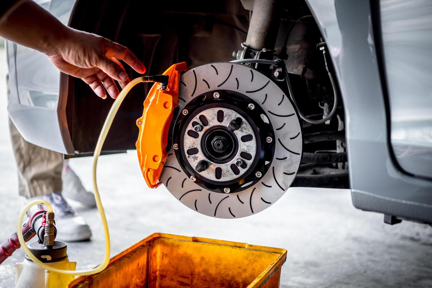 A person is holding an orange hose to a car's brake photo
