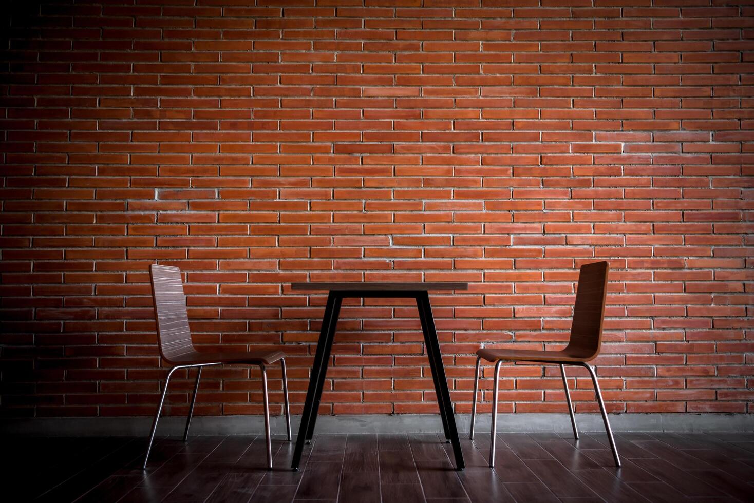 Two chairs and a table in front of a brick wall photo