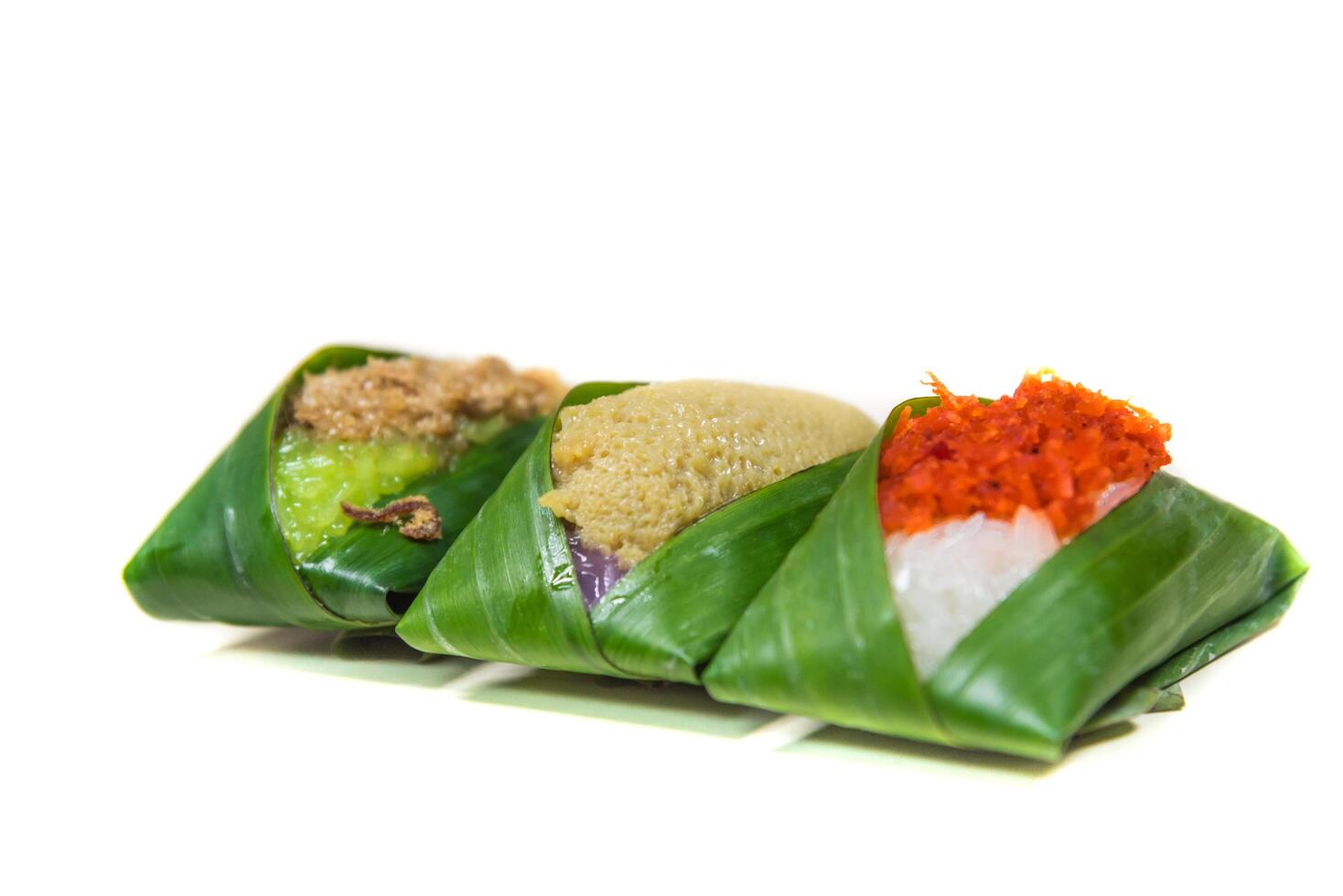 Three different types of food wrapped in banana leaves photo