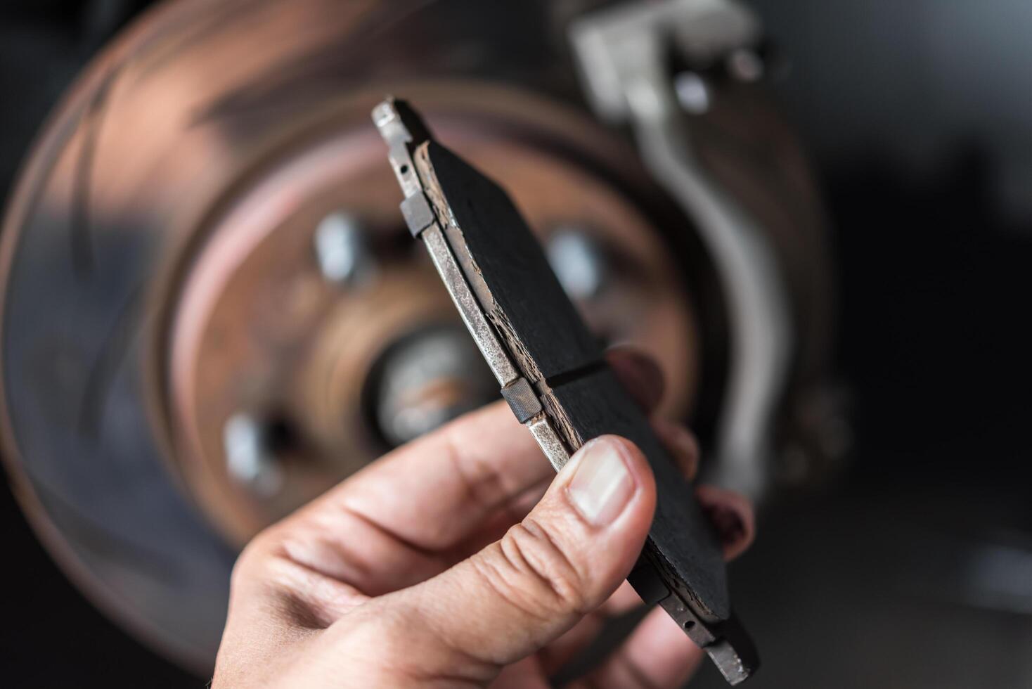 A person holding a brake disc in front of a car photo