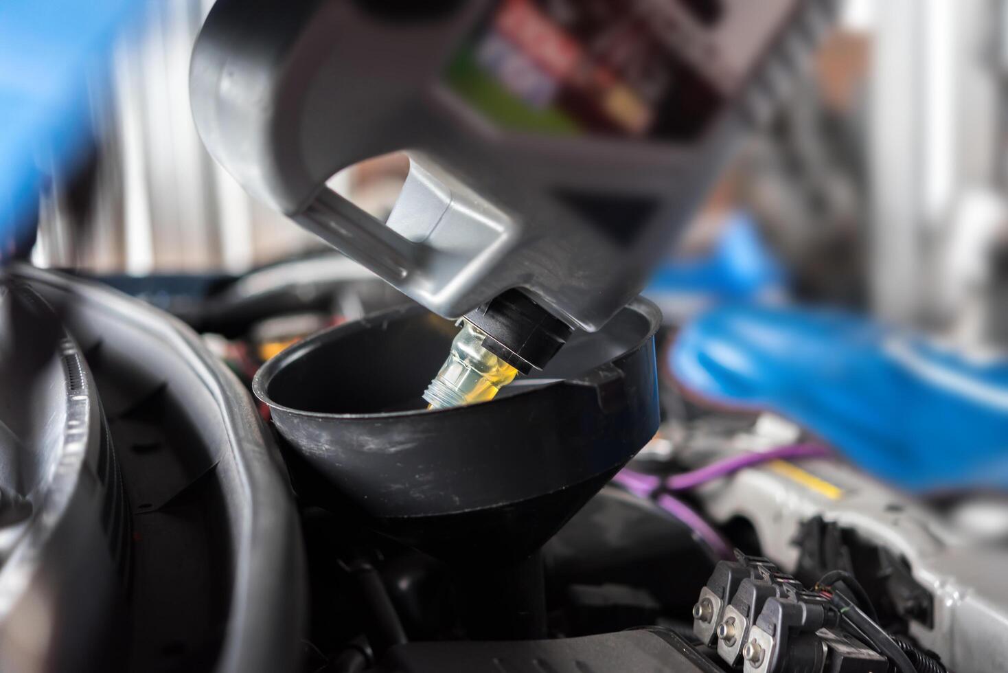 Car mechanic fills a fresh lubricant engine oil photo