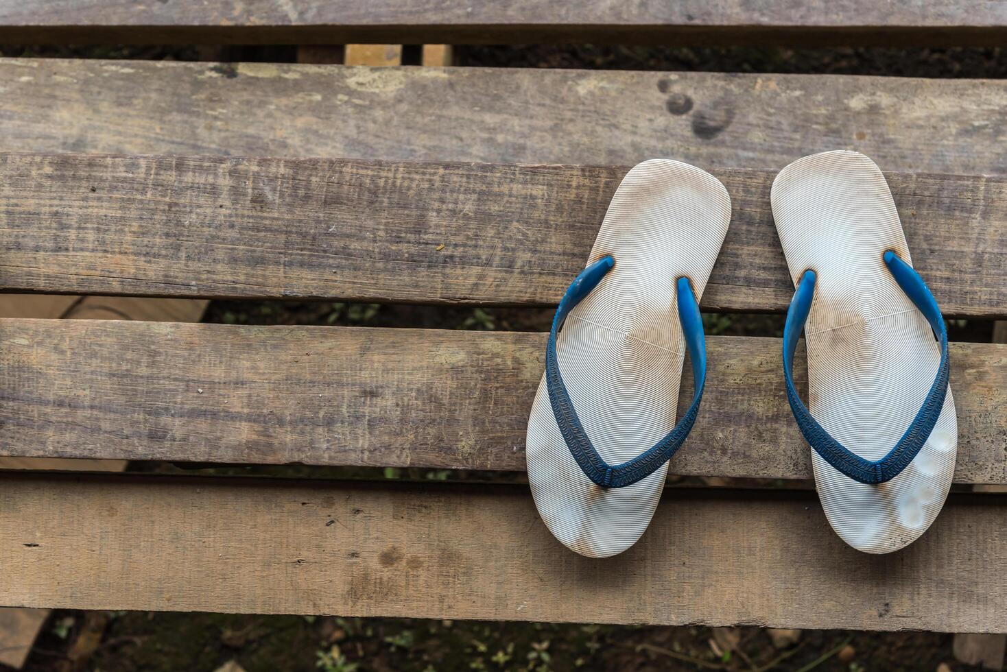 A pair of flip flops are sitting on a wooden bench photo
