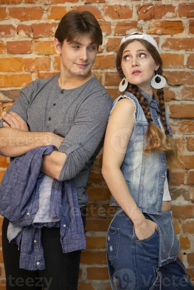 Vertical guy and girl are standing against a brick wall. photo