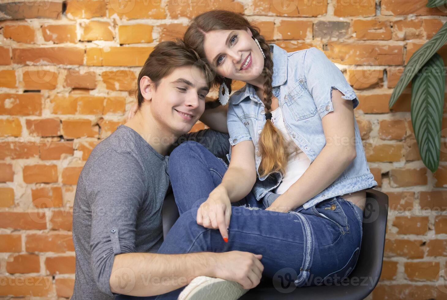A guy and a girl in jeans clothes on a background of a brick wall on a background of a brick wall photo