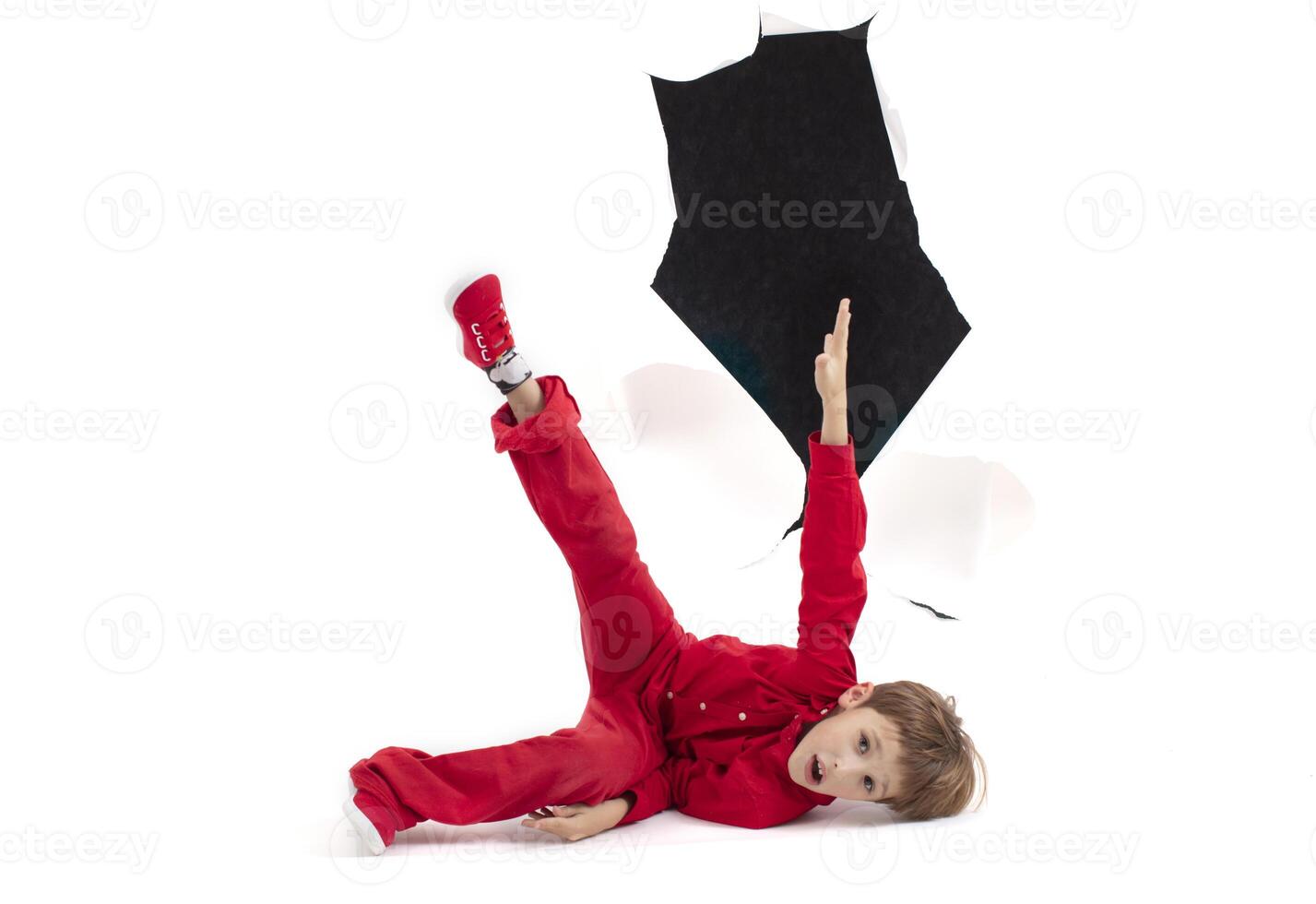 A child from a hole in paper. Boy shows cardboard. Fall out of the billboard photo