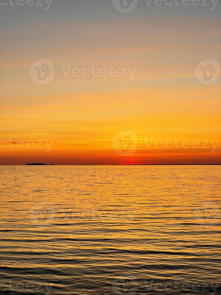 Calm sunset over the sea. The sky is painted with bright colors. Beautiful summer evening at the beach. Vertical photo. photo
