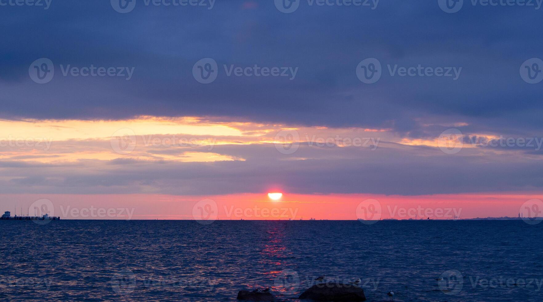 Scenic sunset over the sea. The sun is peeking out from behind the clouds. photo
