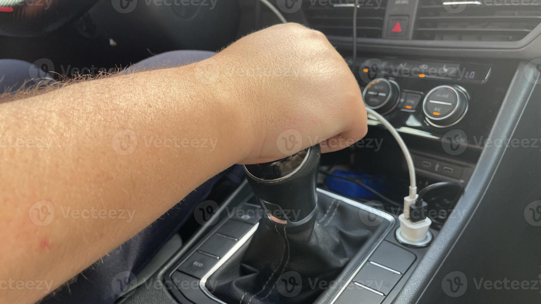 A person's hand is holding a car's shift knob photo