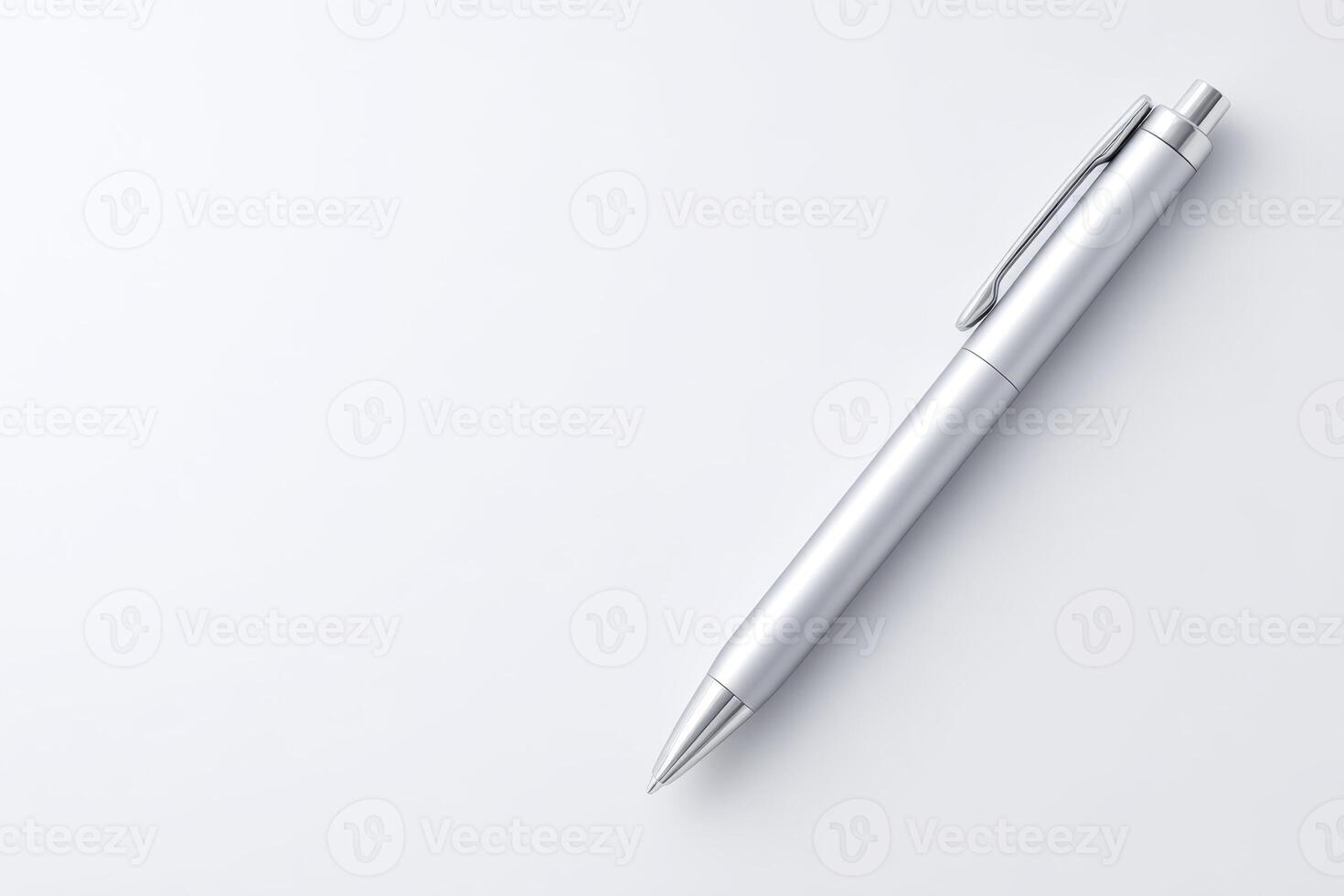 Sleek silver pen with a convenient clip rests diagonally on a pristine white surface, casting a shadow. photo