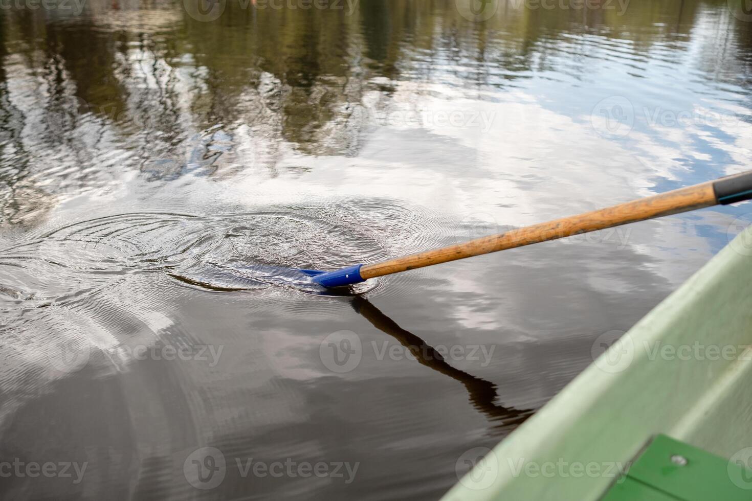 Rowing a Boat on a Calm Lake With Reflections of Trees Under a Cloudy Sky photo