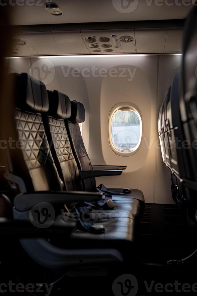 Empty Airplane Interior With Three Dark Seats Beside a Window During Daytime photo