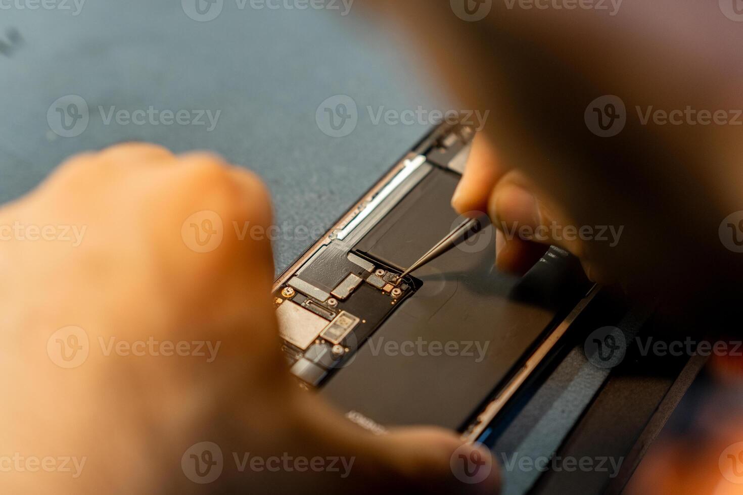 Skilled Technician Performs Phone Repair With Precision Tools During the Day in a Modern Workshop Environment photo