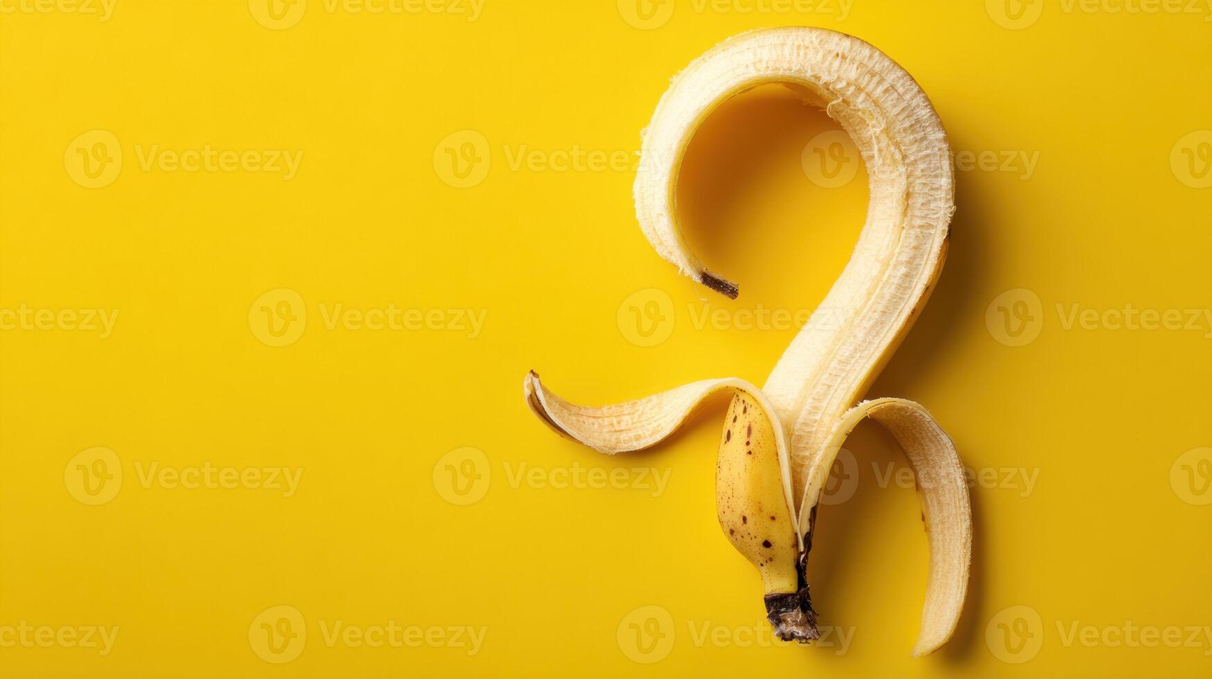 Curled Banana Peel Forms a Question Mark Shape on Vibrant Yellow Backdrop, Evoking Humor and Curiosity in a Whimsical Fruit Composition photo