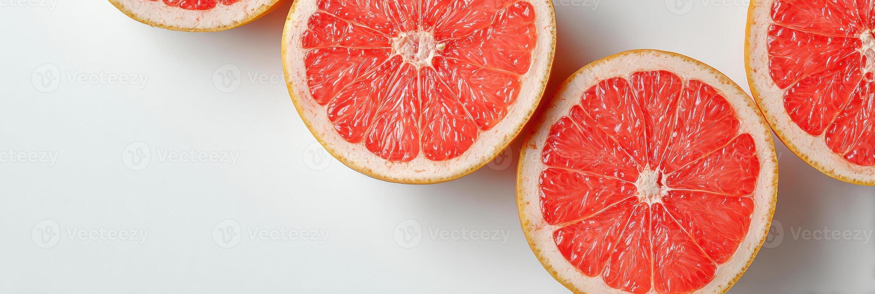 Grapefruit Halves Arranged Diagonally on a Clean White Surface Showcasing Vibrant Pink Flesh and Rind Textures photo