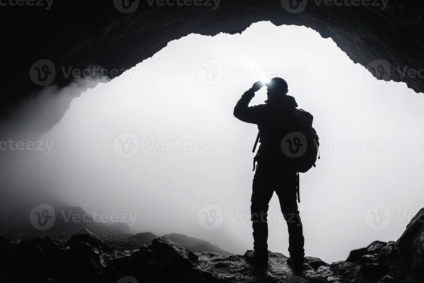 A man standing in front of a cave with fog photo