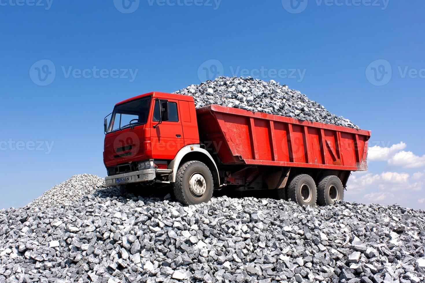 A red dump truck is sitting on top of a pile of gravel photo
