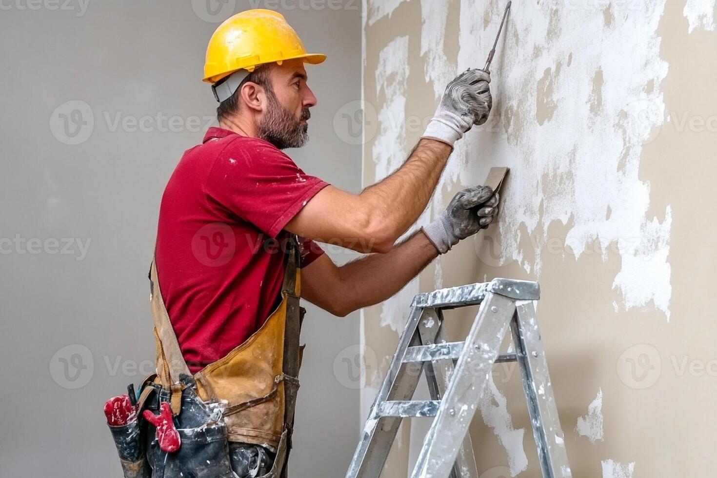 A man in a hard hat and red shirt is painting a wall photo