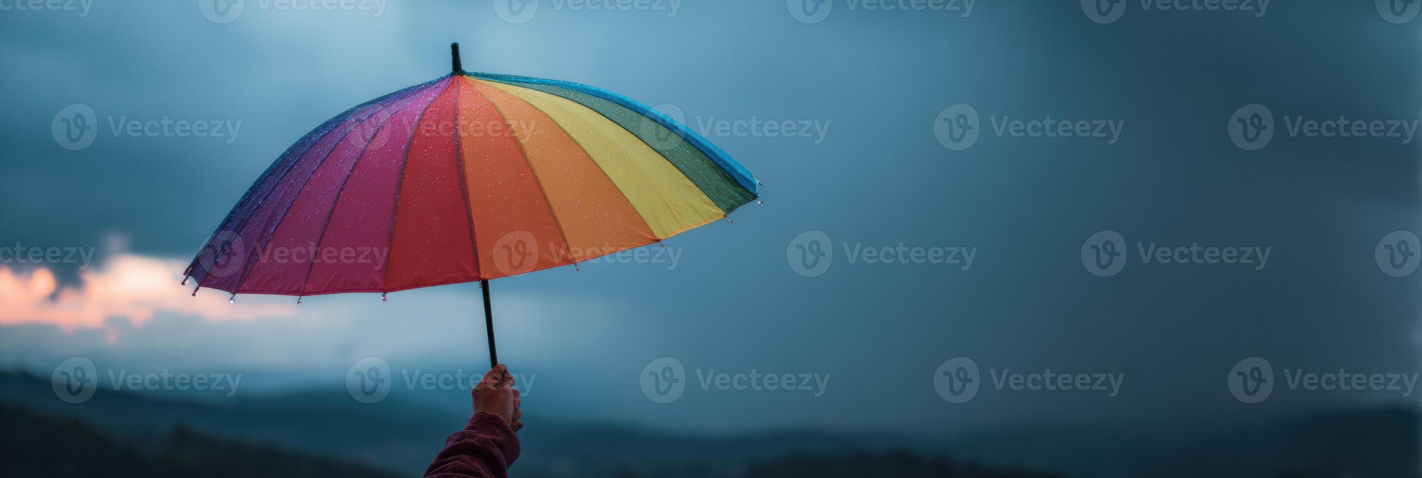 Holding a Rainbow Umbrella Against Stormy Skies, a Symbol of Hope and Support in Challenging Times photo