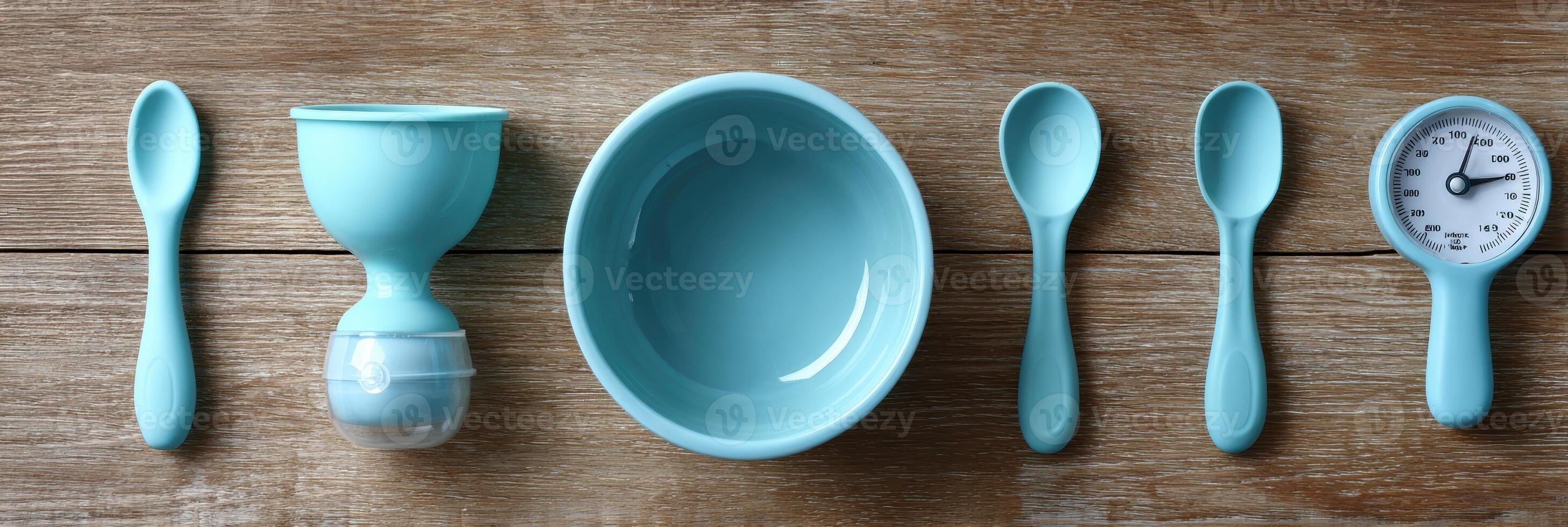 Feeding Tools Arranged on Wooden Surface With Scoop, Timer, and Bowl in Calming Blue Color photo