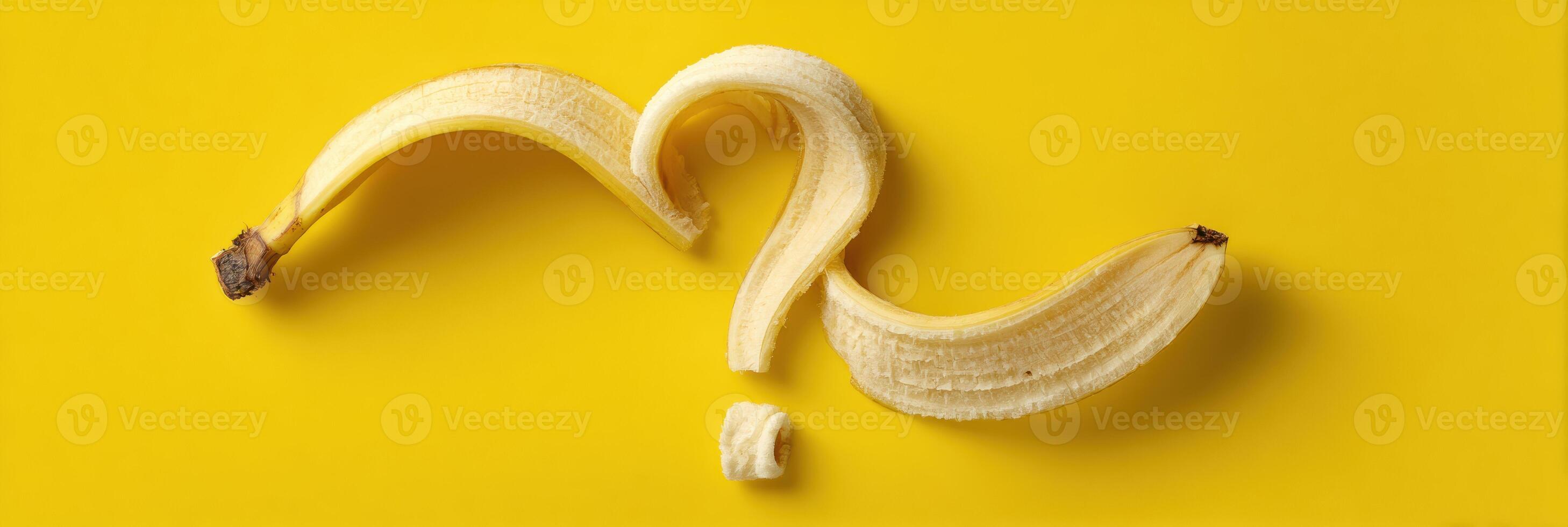 Curled Banana Peel Forming a Whimsical Question Mark on a Bright Yellow Background photo