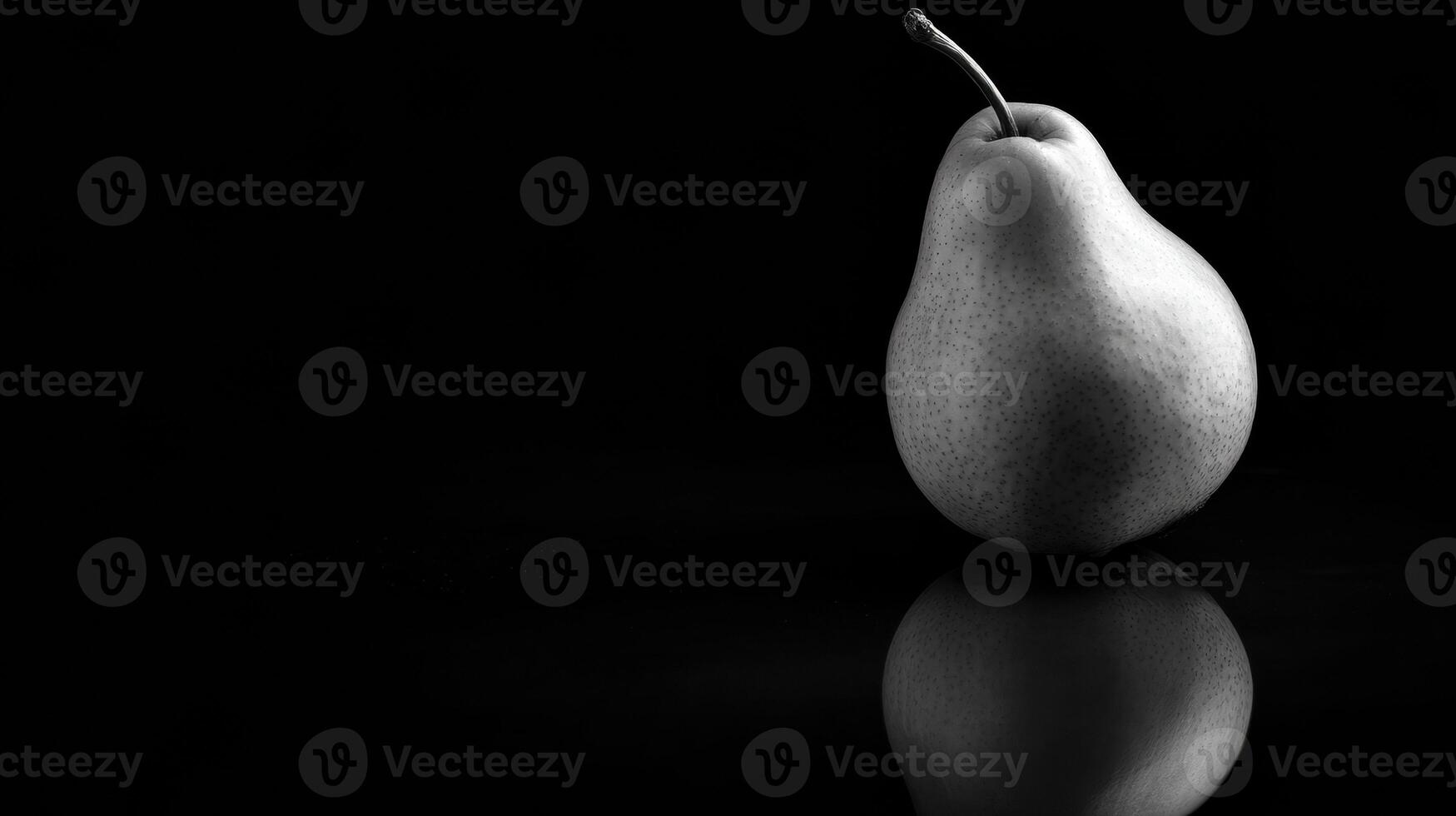 Single Pear Illuminated by Dramatic Lighting on Reflective Black Glass With a Blank Top Margin During a Still Life Setting photo