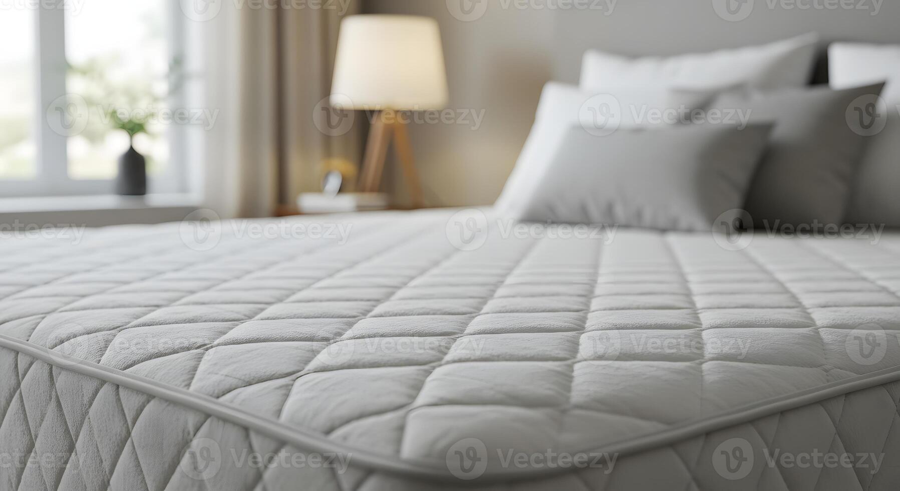 Close up of a comfortable white quilted mattress with pillows and a lamp in a bright bedroom photo