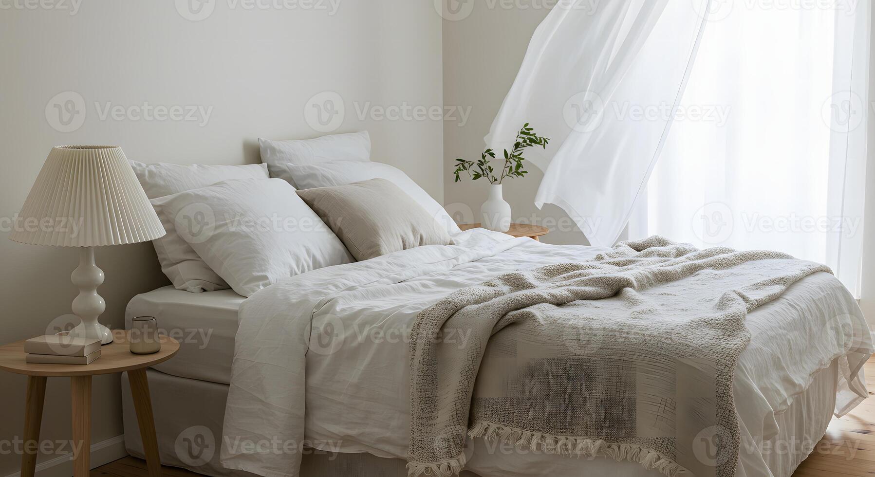 Serene bedroom with a neatly made bed a textured throw blanket and sheer curtains blowing gently in the breeze photo