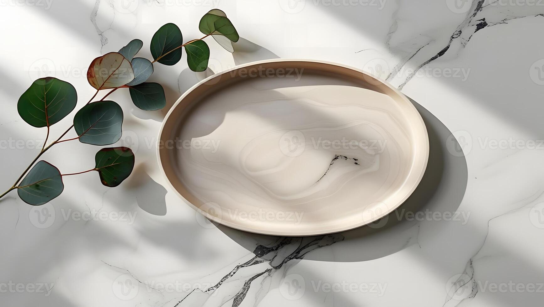 Minimalist arrangement of eucalyptus leaves on a marble surface with a decorative plate photo
