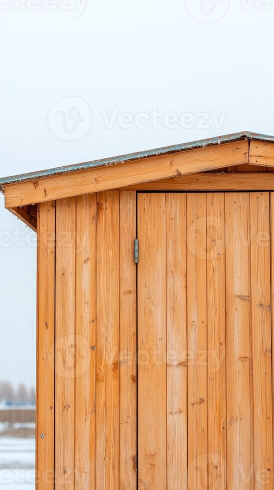 Rustic Wooden Shed Detail in Winter Close-up of Natural Timber Paneling and Roof Edge Against a Soft, Overcast Sky, Highlighting Architectural Simplicity and Warm Wood Tones photo