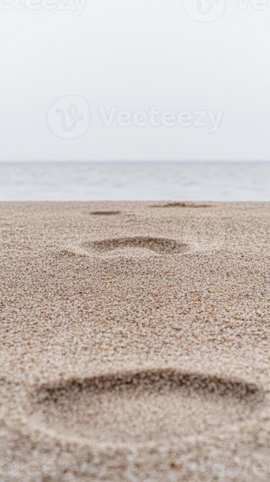 Sublime Footprints Etched in Golden Sand, Stretching Towards the Vast, Calm Ocean and Distant Horizon Under a Serene, Overcast Sky. photo