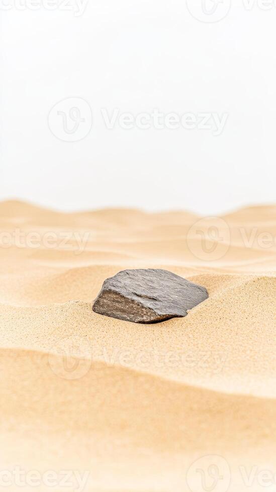 Minimalist desert landscape featuring a solitary dark rock nestled amidst the gentle undulations of golden sand, exuding tranquility and natural beauty. photo