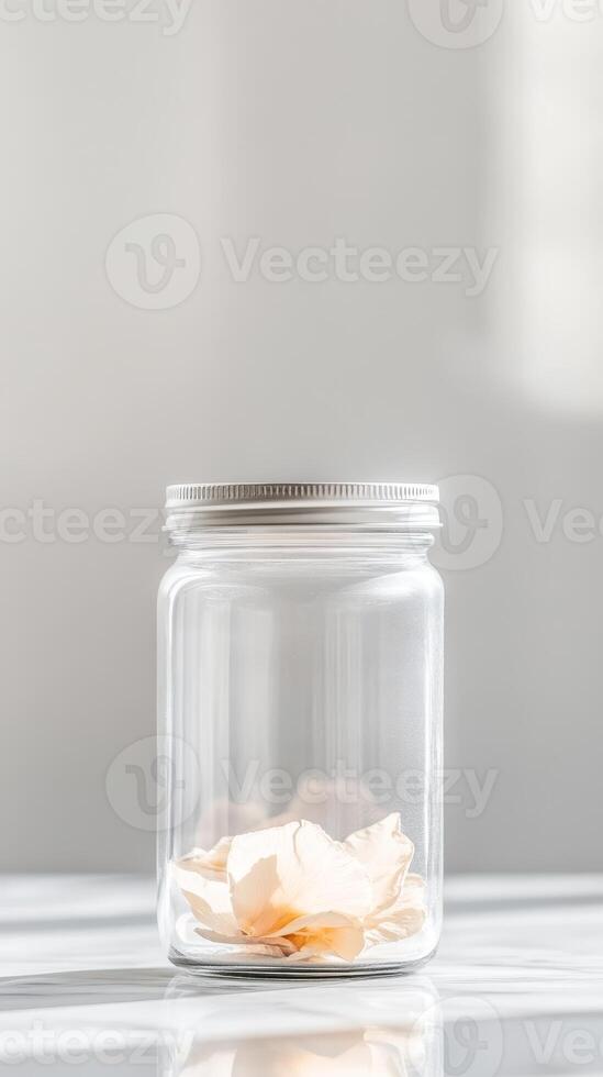 Delicate Dried Flower Petals in a Clear Glass Jar A Minimalist Botanical Still Life Capturing Serene Light and Gentle Reflections photo
