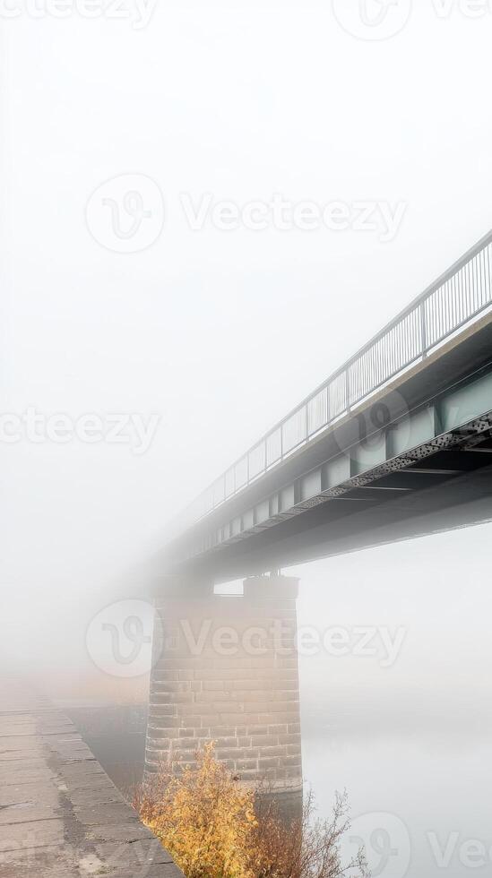 Ethereal Bridge Veiled in Dense Fog A Mystical Crossing Over Water on a Muted Autumn Day, Evoking Serenity and Solitude photo