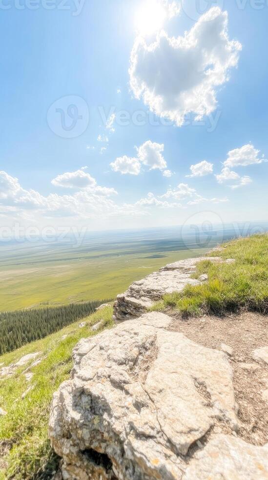 Breathtaking Mountain View Expansive Green Plains and Sunny Blue Sky from a Scenic Cliff Overlook, Capturing Nature's Grandeur and Serenity photo