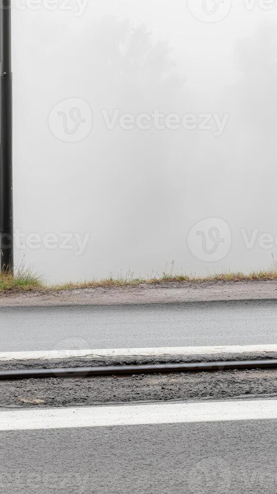A Moody Morning Dense Fog Obscures the Horizon Over a Wet Road and Tram Track, Creating a Serene and Mysterious Urban Landscape. photo